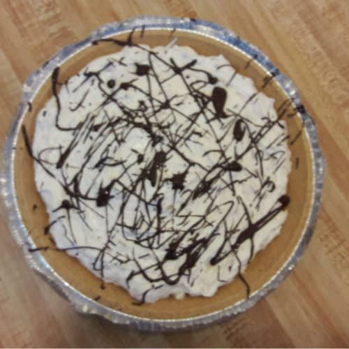 No bake peanut butter pie drizzled with melted chocolate, sitting on a table