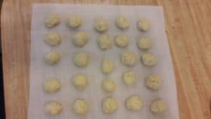 Rows of formed donut holes sitting on parchment paper.