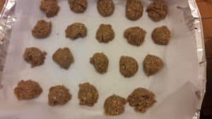 Parchment-paper lined baking sheet containing rows of oatmeal cookie dough balls