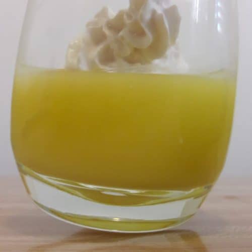 Glass cup containing lemon curd and a dollop of whipped cream on top