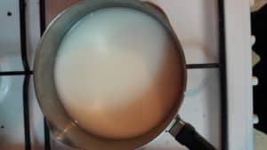 small pot on the stove containing a milky mixture of water, sugar, and cornstarch