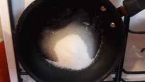 Sugar and water in a frying pan on the stove.