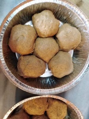 Small round baking pan with six balls of challah dough in it.